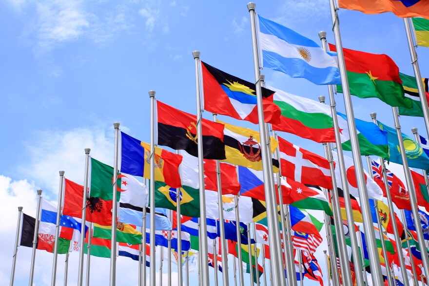 An array of world flags fly on poles