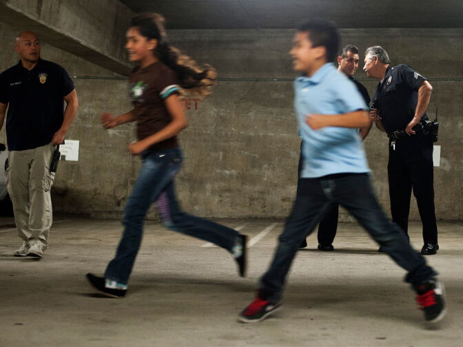 PAL Officer Edward Andalis, left, and supervisors Sgts. James Townsend and Manuel Ramirez watch as kids run laps through the parking garage on Tuesday evening.