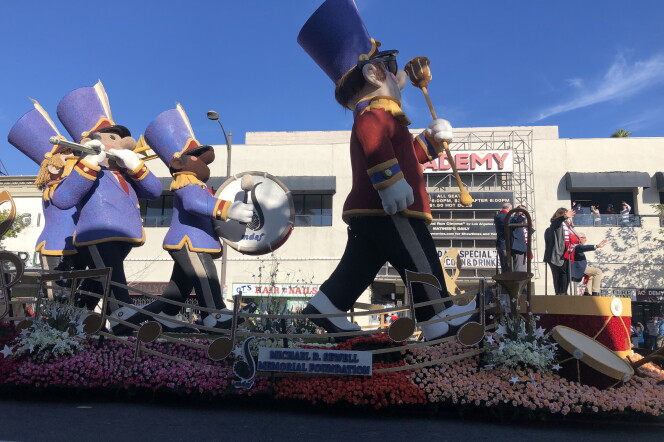 A float is covered in roses and carries a marching band leader figure, followed by figures playing the drums, flute and trombone. A sign reads: "The Michael D. Sewell Memorial Foundation."
