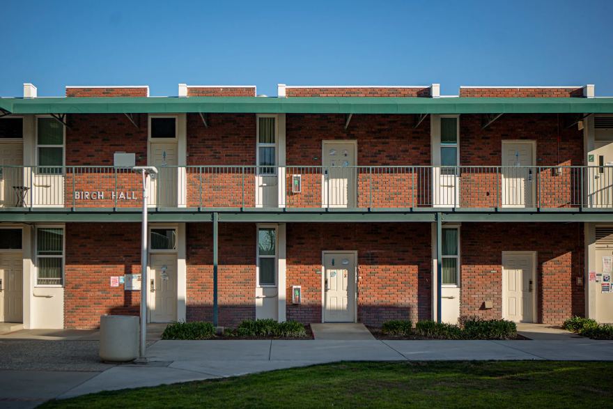 A two-story building features white doors and brick walls.