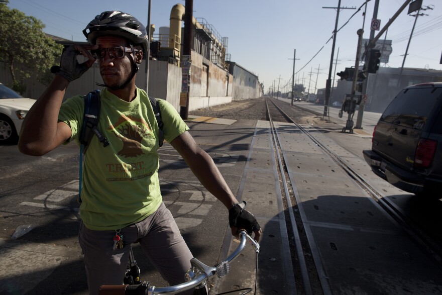 Malcolm Harris crosses the defunct train tracks along Slauson Avenue and South San Pedro Street in South Los Angeles. He commutes on a bike along this path, navigating heavy traffic and sketchy roadways. The Metropolitan Transportation Authority is considering turning the eight mile track into a green space that would offer walking and biking paths.