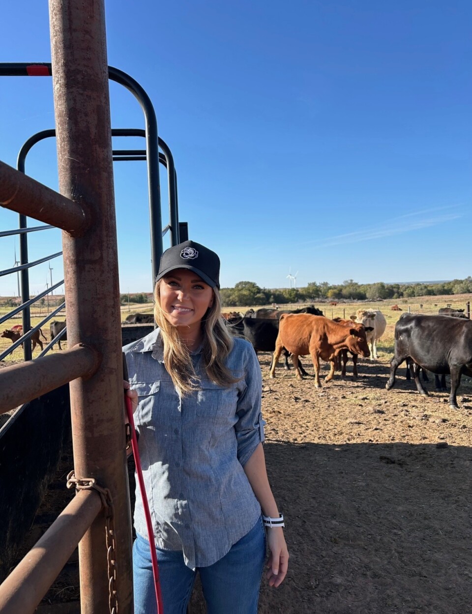 A woman with light-tone skin and long hair stands in a field.
