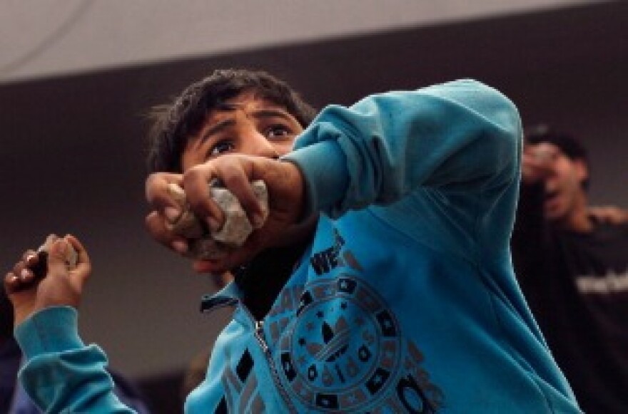 An anti-government protester throws rocks at pro-government supporters near a highway overpass on the edge of Tahrir Square. 