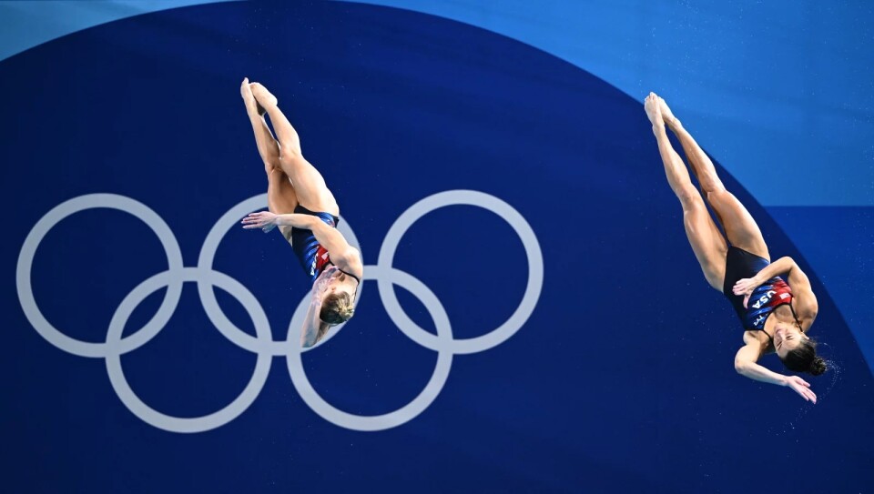 Two divers dive with the olympic logo 