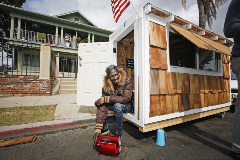 Irene "Smokie" McGhee, a woman who had been sleeping on the streets in a South Los Angeles neighborhood, listens to music on the doorway of her newly built tiny home Thursday, May 7, 2015, in Los Angeles. Smokie said police told her she won’t be bothered as long as she moves the home , small enough to fit in a parking space, every three days. And the structure is so small that it wouldn’t require permits if built on private property, said Luke Zamperini, spokesman for the Building and Safety department.