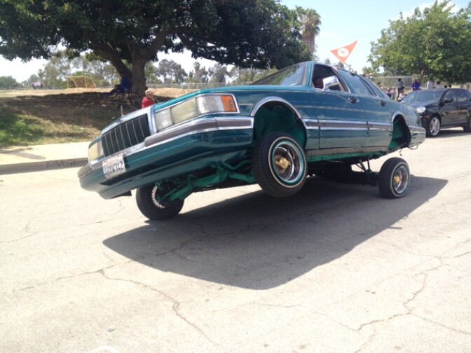 A low-rider car with hydraulics cruises down the street in the "peace ride" event on three wheels. 