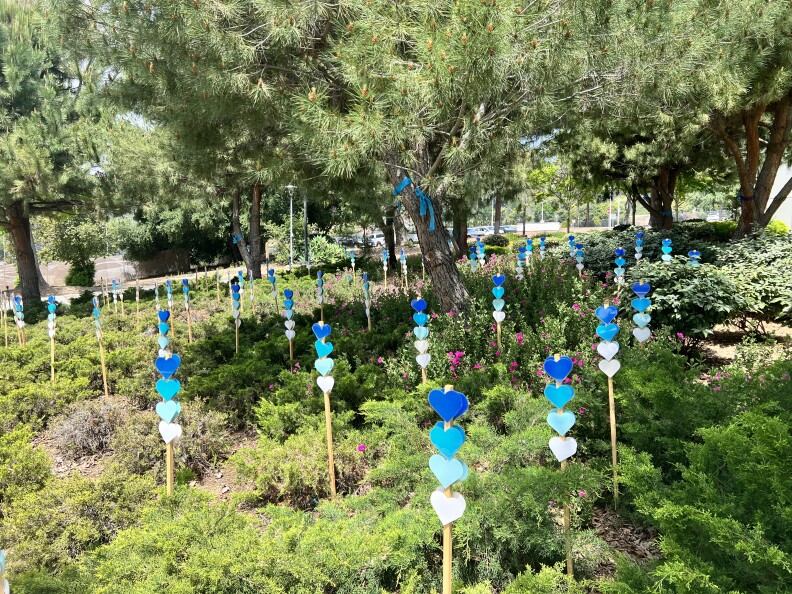 Garden stakes with four blue hearts are planted throughout the REACH garden for the month of May.