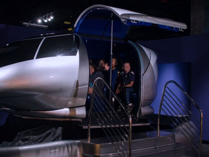 Children get ready to "take off" inside the Pulseworks simulator ride during a preview of Endeavour: The California Story exhibit at the California Science Center.