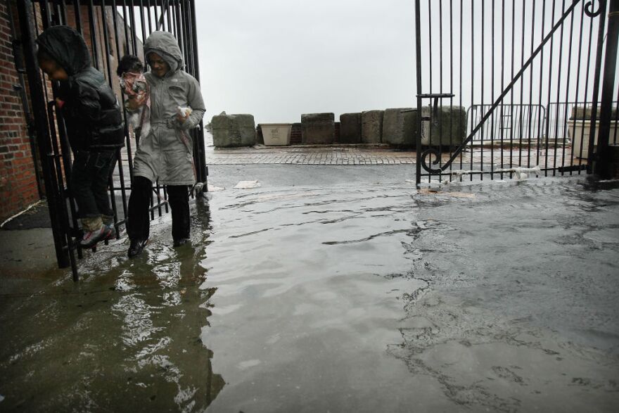 NEW YORK, NY - OCTOBER 29:  People walk through a flooded street as Hurricane Sandy moves closer to the area on October 29, 2012 in the Red Hook section of the Brooklyn borough of New York City. The storm, which threatens 50 million people in the eastern third of the U.S., is expected to bring days of rain, high winds and possibly heavy snow. New York Governor Andrew Cuomo announced the closure of all New York City will  bus, subway and commuter rail service as of Sunday evening.  (Photo by Spencer Platt/Getty Images)