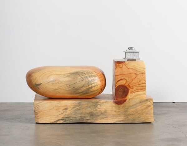  A wood work of art, a bean-shape next to a wood block on top of a longer wooden slab. 