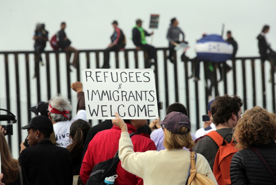 SAN DIEGO, CA - APRIL 29: Pro-migrant caravan demonstrators rally at the west end of the U.S.-Mexico border as pro-migrant demonstrators climb the border wall from the Mexican side on April 29, 2018 in San Diego, California. More than 300 immigrants, the remnants of a caravan of Central Americans that journeyed across Mexico to ask for asylum in the United States, have reached the border to apply for legal entry. (Photo by Bill Wechter/Getty Images)