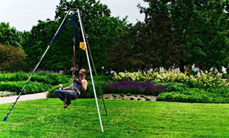 Woman swings in a park with a coffee in hand