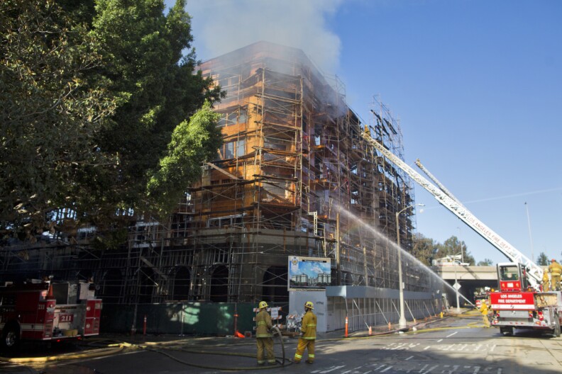 Firefighters spray down smoldering scaffolding after an early-morning fire consumed a seven-story apartment complex that was still under construction in downtown Los Angeles on Monday, Dec. 8, 2014.