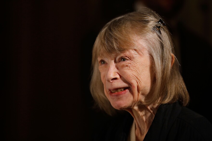 A portrait of Didion smiling and looking off into the distance.