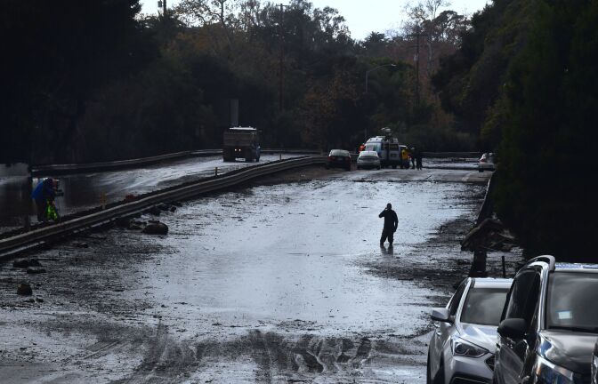 A man wades in a flooded section of the US 101 freeway near the San Ysidro exit in Montecito, California on January 9, 2018. 
Mudslides unleashed by a ferocious storm demolished homes in southern California and killed at least 13 people, police said Tuesday. / AFP PHOTO / FREDERIC J. BROWN        (Photo credit should read FREDERIC J. BROWN/AFP/Getty Images)