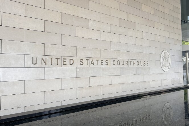 The exterior beige stone exterior has the words "United States Courthouse" engraved with the American federal seal beside it. The letters are reflected from a stone water fountain below the stone exterior wall at the federal courthouse in downtown Los Angeles. 