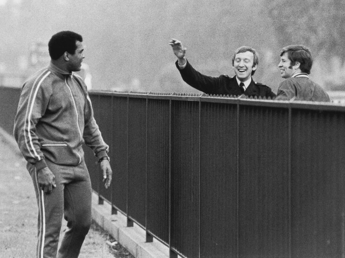 1977: American heavyweight boxer Muhammad Ali is greeted by two police officers in Hyde Park, London, during the boxer's early morning run.