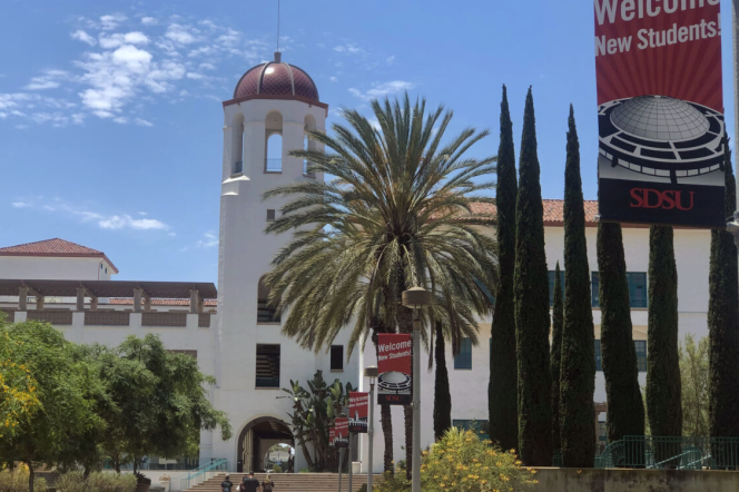 A white building with a bell tower and a dome alongside other buildings on a university campus 