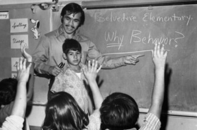 A teacher points to the blackboard at Belvedere Elementary School as students raise their hands. 
