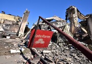 A State Farm insurance sign leans against the remains of a burnt building