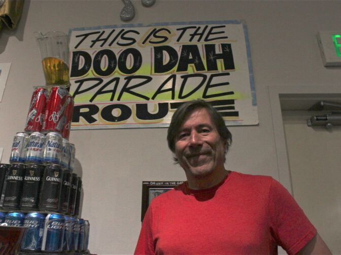 Tom Coston standing at the exhibit "What a Long Strange Trip It's Been: 35 Years of the Pasadena Doo Parade" at the Pasadena Museum of History.
