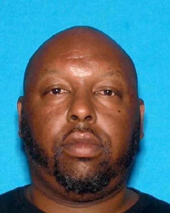 A man with dark-tone skin, a bald head and facial hair in a mug shot.