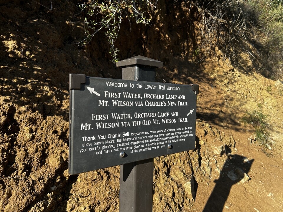 A photo of a sign on a dirt trail. 
