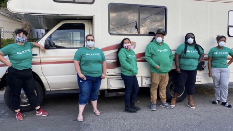 Six members of Sacramento's Mental Health First team pose for a photo in front of a recreational vehicle.