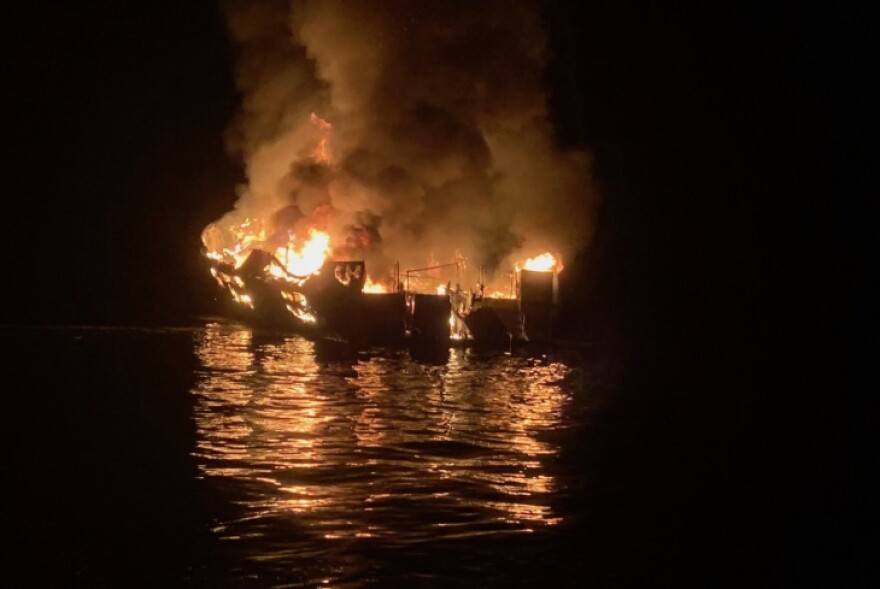 A boat on the water on fire at night time.