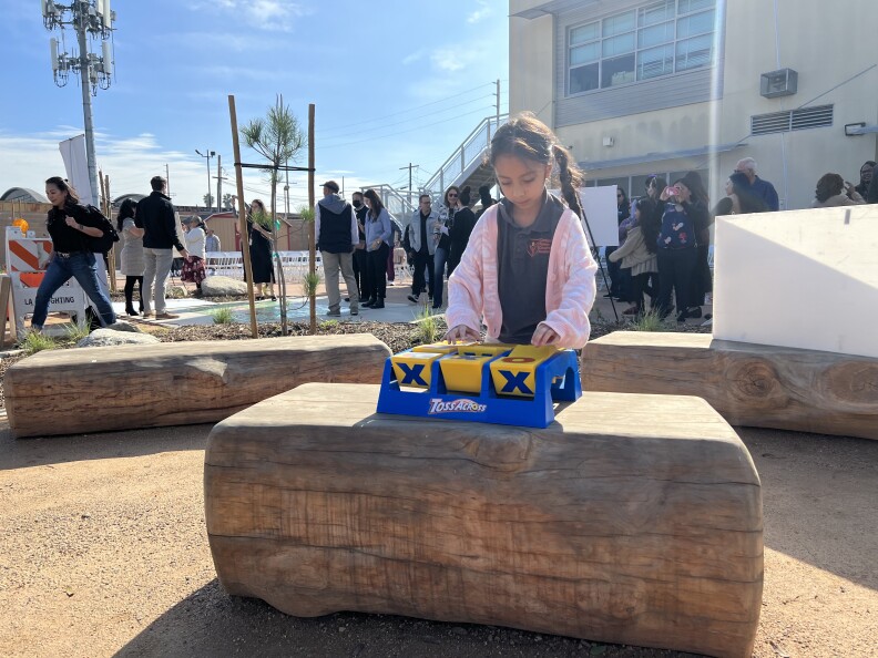 A brown skinned girl plays with a tic-tac-toe game