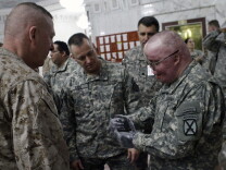 Retired U.S. Army Sgt. 1st Class Mike Schlitz, who suffered burns over 85 percent of his body by a roadside bomb in 2007, right, talks about his new prosthetic hands after a ceremony at al-Faw palace in Baghdad, Iraq, Sunday, Jan. 31, 2010. He later received reconstructive surgery through Operation Mend.