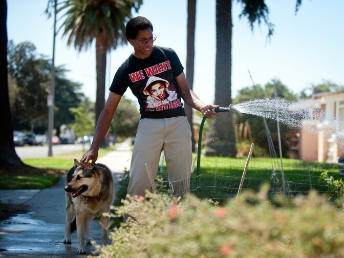 John Parker waters his garden with his dog, Diamond. Parker first planted herbs in the parkway garden a year ago.