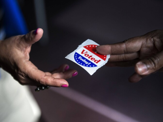 A poll worker hands out 'I Voted' stickers. 