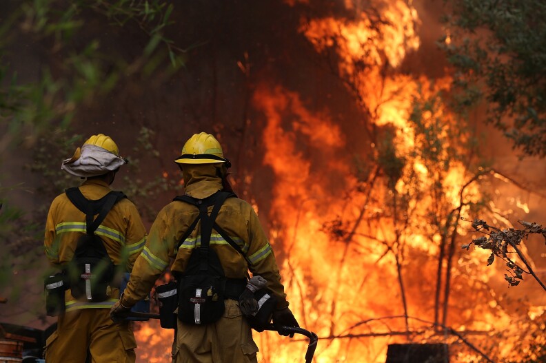 Two firefighters stand before a blaze in Yosemite National Park