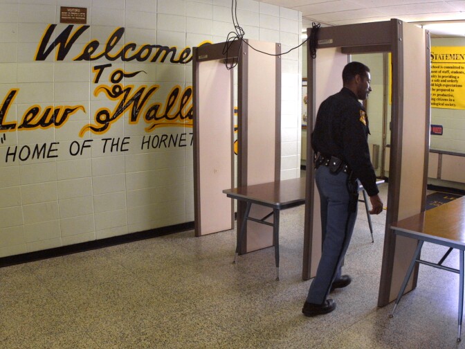 Police Officer Jeff Tatum passes through a metal detector at Lew Wallace High School after 16-year-old sophomore Neal Boyd, Jr. was fatally shot outside the building before classes began. 