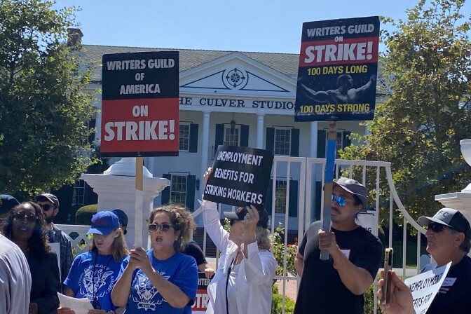 Striking writers and actors crowd the area outside Amazon Studios in Culver City. One person holds a sign that reads: Unemployment Benefits for Striking Workers. 