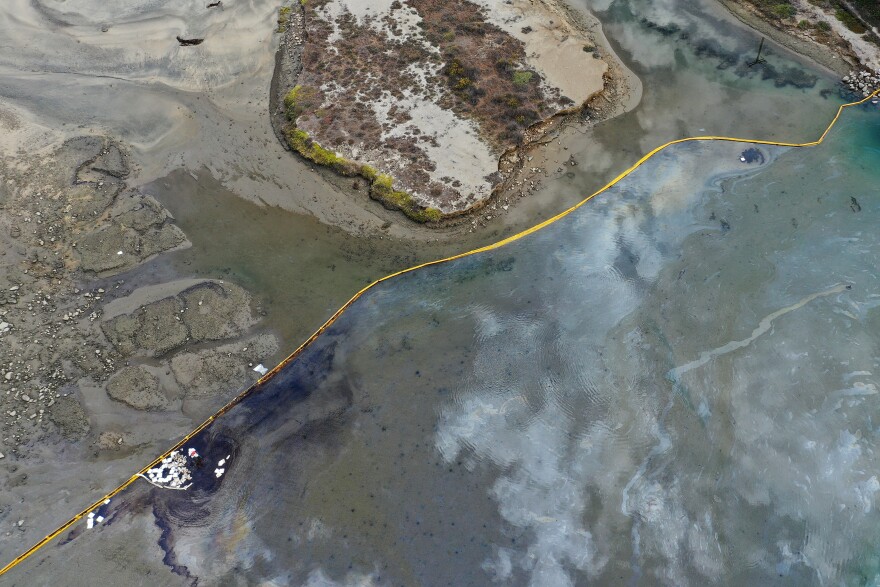 An aerial view shows the Huntington Beach coastline and a massive oil spill in the water.