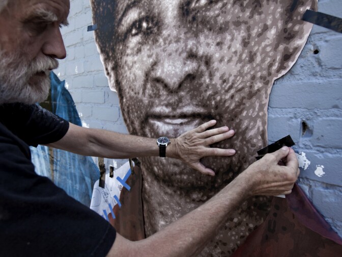 Kent Twitchell tapes the portrait of Loretta Claiborne on a wall. This is one figure in his mural honoring the 2015 Special Olympics. 