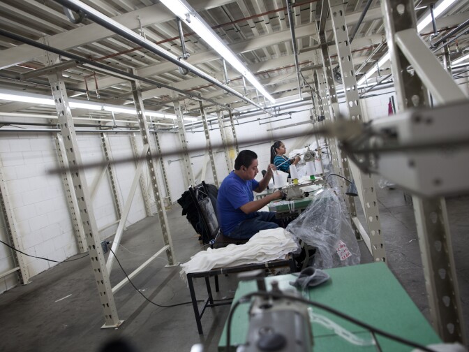 Julio Gonzalez and Mercedes Luz sew shirts at the Youth Monument warehouse in downtown Los Angeles.