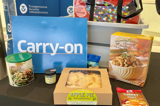 packaged thanksgiving food on a table next to TSA signs and a giant one that says "Carry-on"