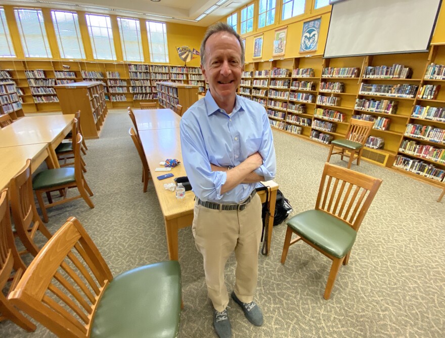 Austin Beutner, outgoing superintendent of the L.A. Unified School District, is shown wearing a blue dress shirt and beige pants standing in front of a long rectangular table surrounded by full bookshelves in the library of Paul Revere Middle School in Pacific Palisades.