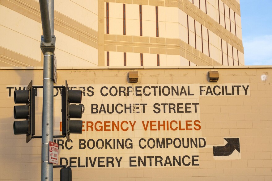 The side of Twin Towers jails reads — in part — in painted letters: Emergency Vehicles, Booking Compound, Delivery entrance, with a black arrow pointed to the right and slightly upward.