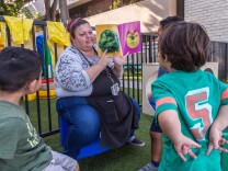 Rosa Lopez reads a book to kids at the Mexican American Opportunity Fund child care center in Norwalk. She's been in the child care field for 24 years and makes under $15/hr.