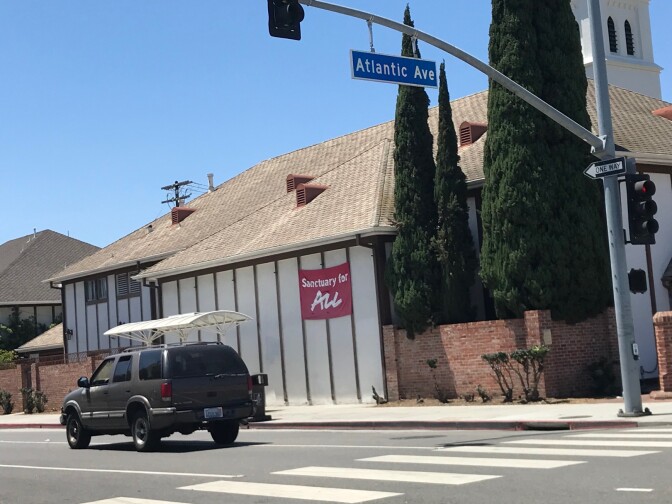 Outside St. Luke's Episcopal Church, a banner reads 'Sanctuary for All.'