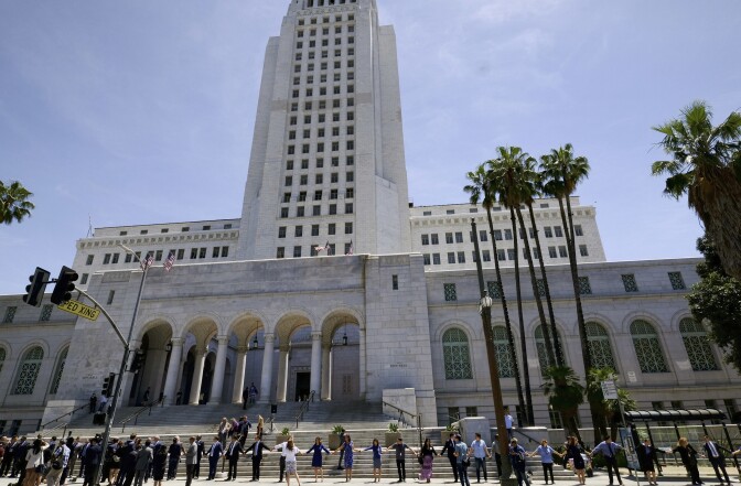 Los Angeles City Council members and others participate in a ''Hands Around City Hall'' event — a symbolic gesture of "cross-cultural unity" — on April 28, 2017 in downtown Los Angeles in remembrance of the L.A. Riots' 25th anniversary. The riots broke out on April 29, 1992.
