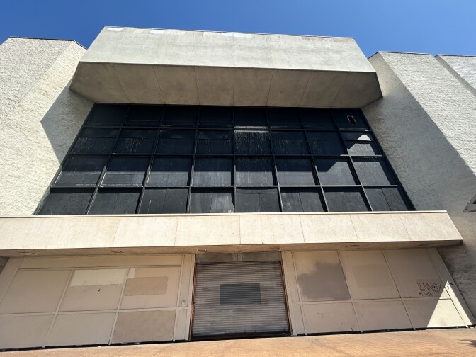 A large beige abandoned building that is boarded up 