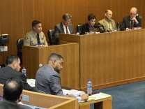 At Civilian Oversight Commission May 24, 2022 hearing on deputy gangs, Lt. Larry Waldie, in uniform, sits in the witness box. To his left are three men and a woman, and in the foreground two men sit writing at a table.