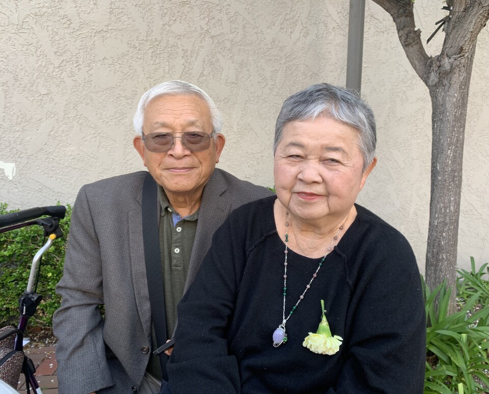A Taiwanese American man and woman in their 80s sit next together for posed photo.