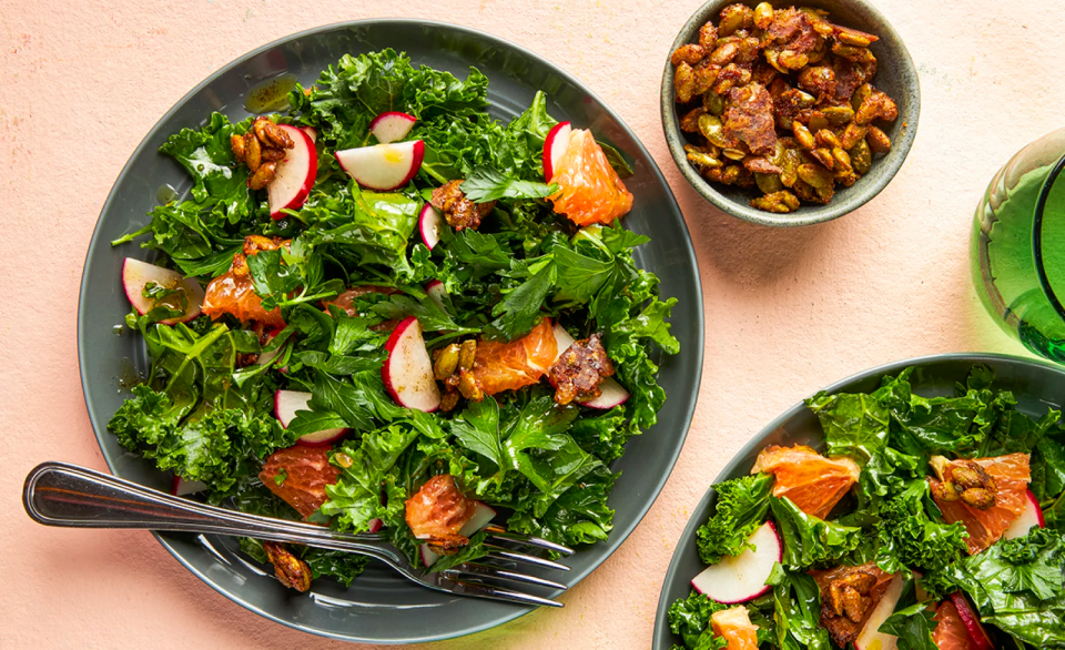 Plates of salad with apple slices, citrus, and a side bowl of nuts