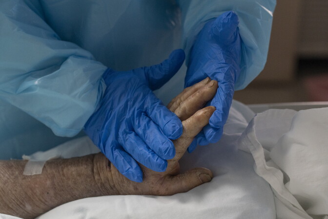 HOUSTON, TX - NOVEMBER 25: (EDITORIAL USE ONLY) A medical staff member gently massages a hand of a patient suffering from COVID-19 in the COVID-19 intensive care unit at the United Memorial Medical Center on November 25, 2020 in Houston, Texas. According to reports, Texas has reached over 1,210,000 cases, including over 21,300 deaths.  (Photo by Go Nakamura/Getty Images)